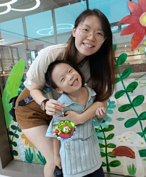 Children smiling as they decorate dragon boat with mom