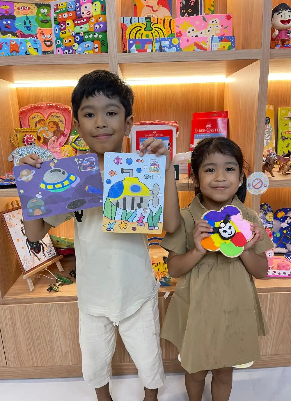 Children proudly holding their finished sand artwork