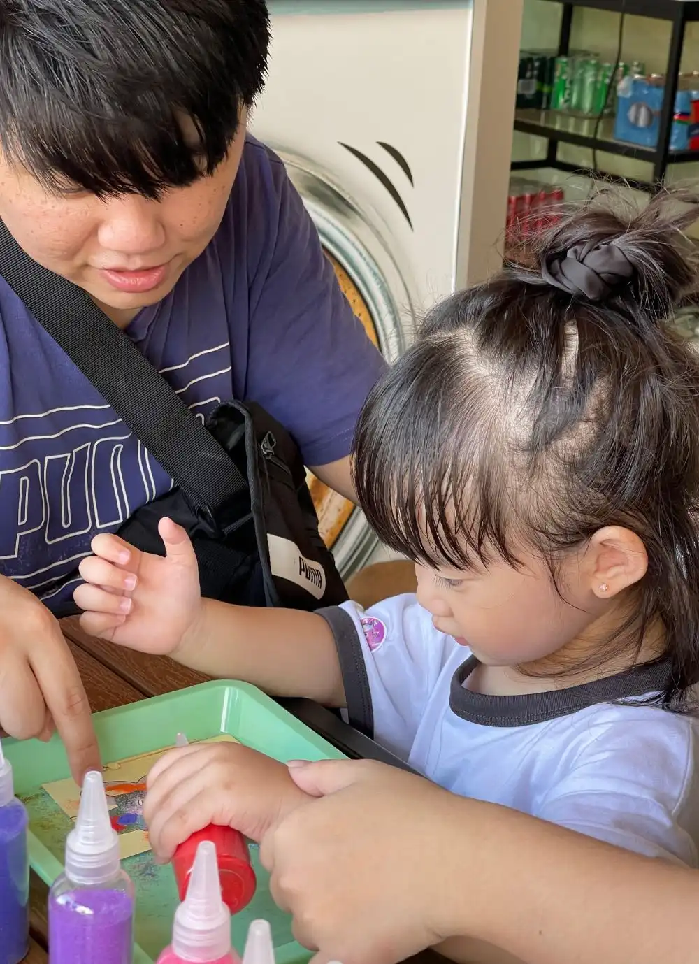 A parent and child working together on a sand art design at Art Journey Singapore.