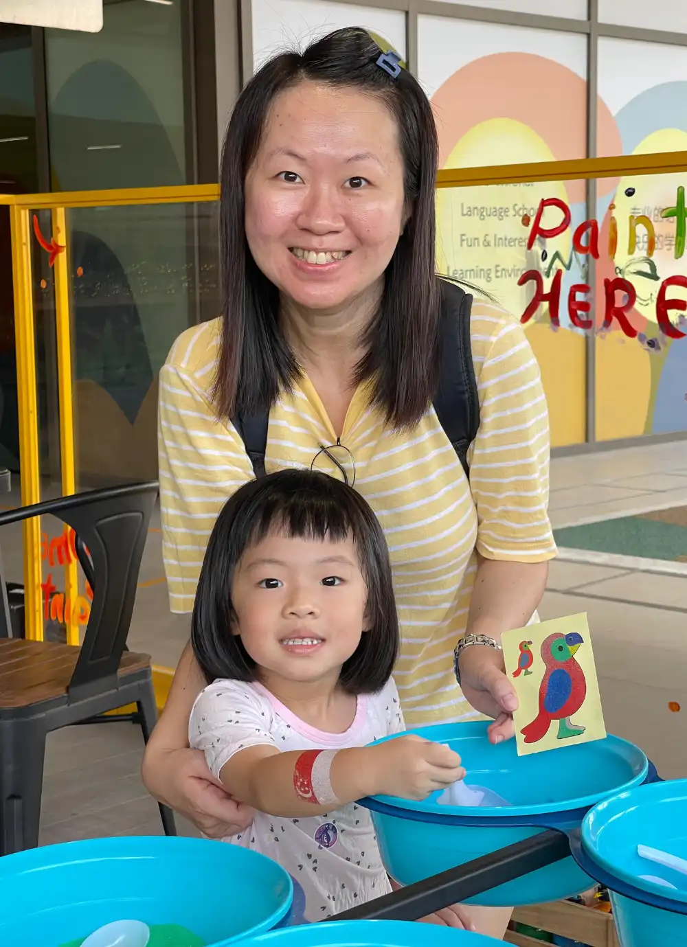 parent assisting their child with sand artwork