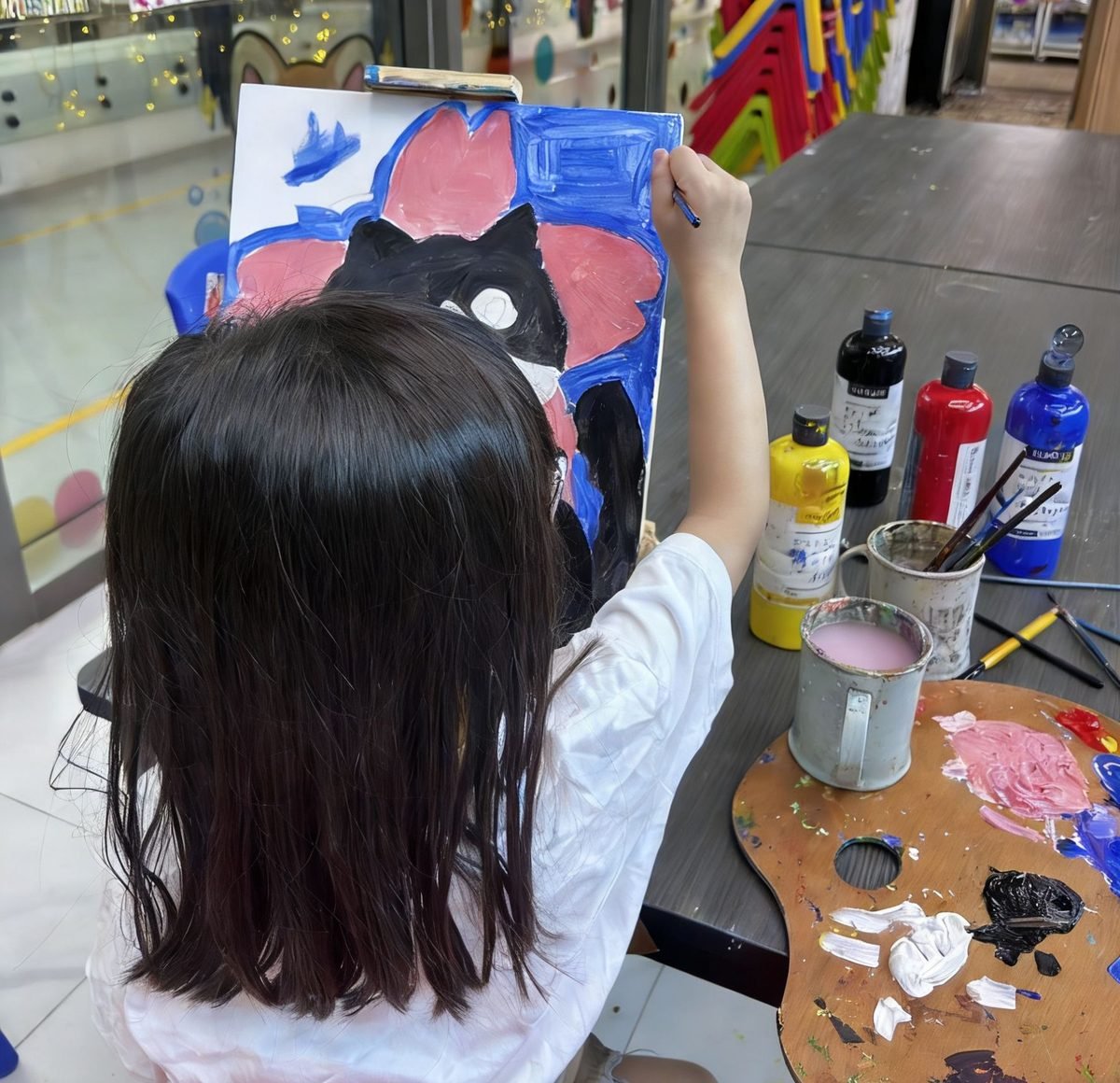Young child painting a colourful canvas on an easel during an art workshop session at Art Journey Singapore