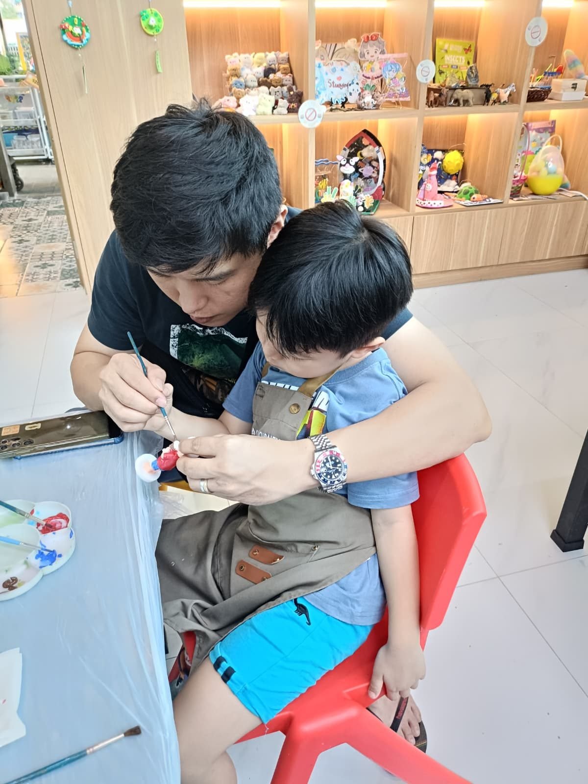 Father and young son painting a 3D figurine together during an art jamming session at Art Journey Singapore studio