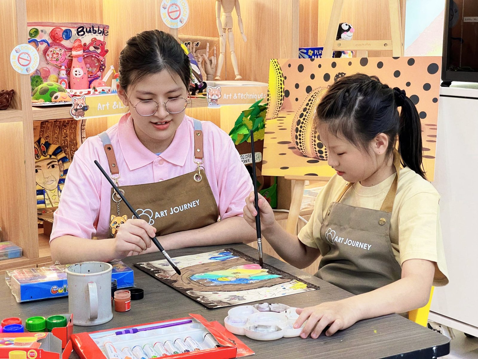 Young child painting a colourful canvas on an easel during an art workshop session at Art Journey Singapore
