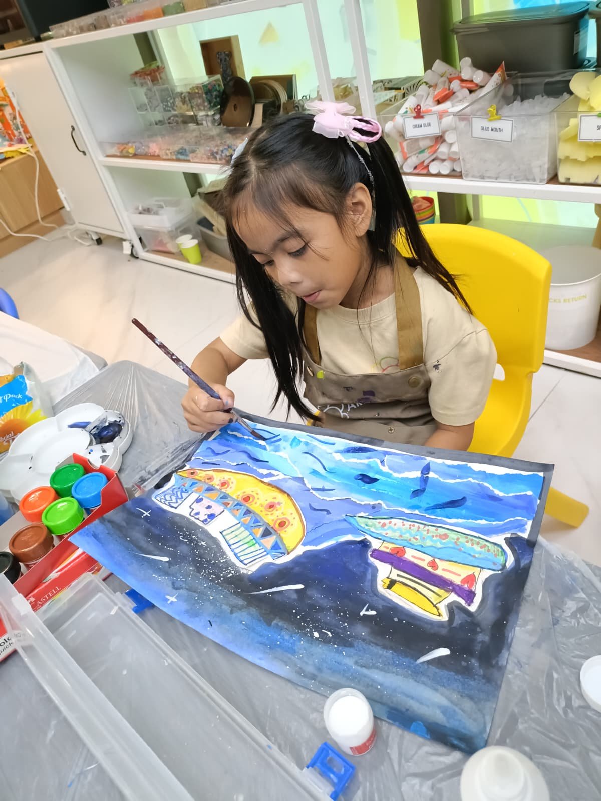 Child painting a beautiful sea scene at Art Journey workshop
