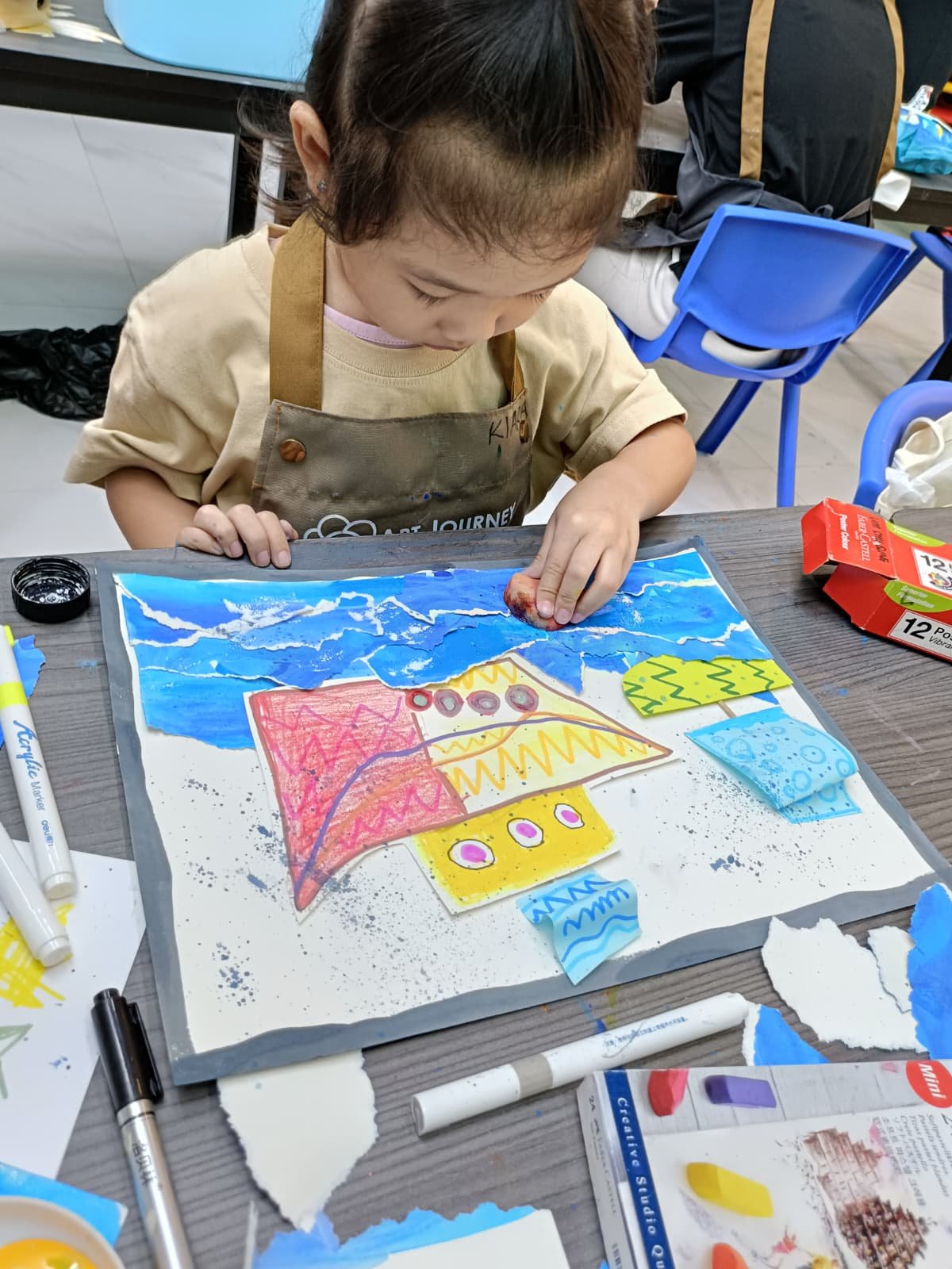 Child creating mixed-media collage artwork