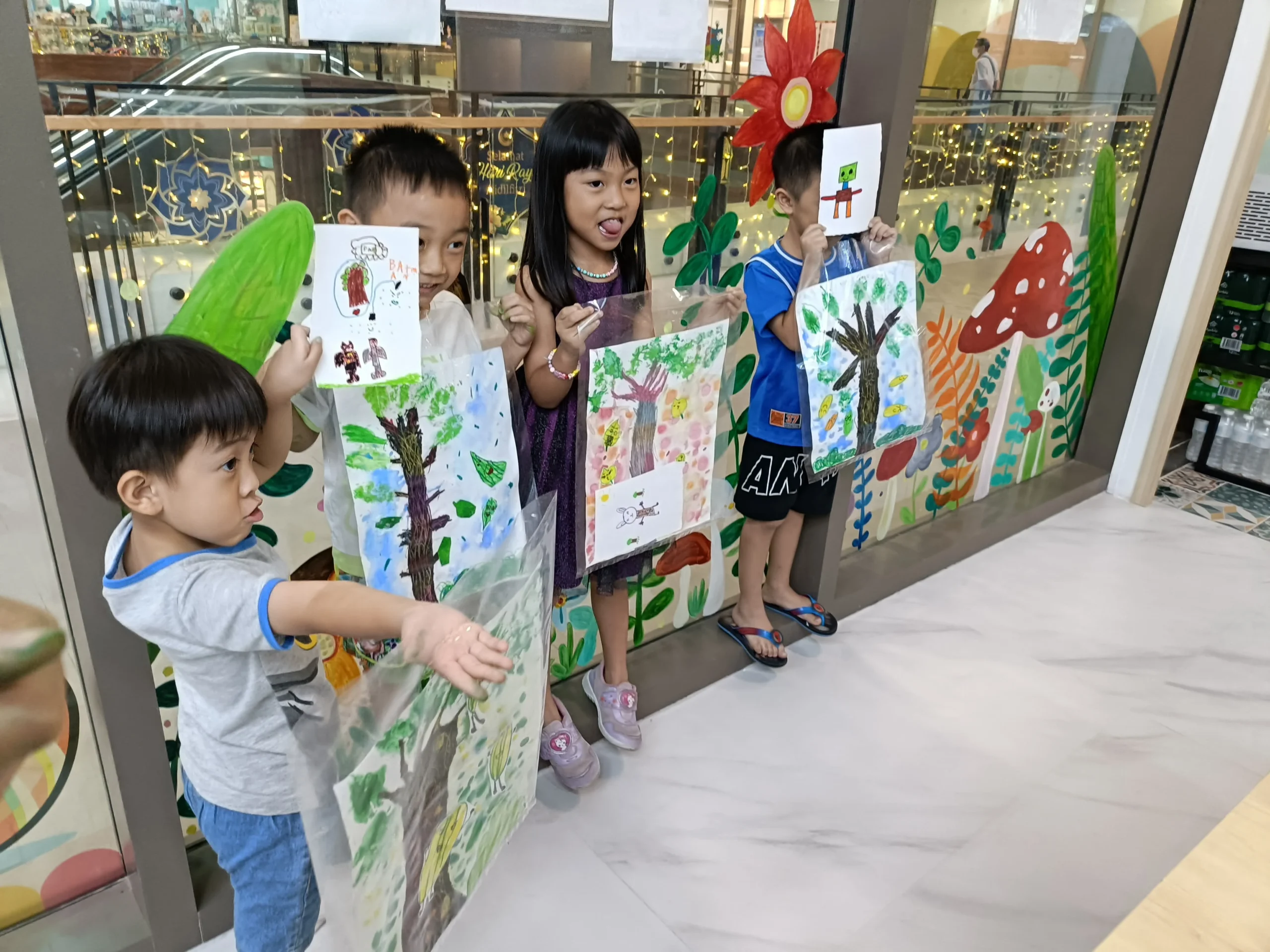 Children proudly displaying their finished art projects from a creative workshop at Art Journey Singapore
