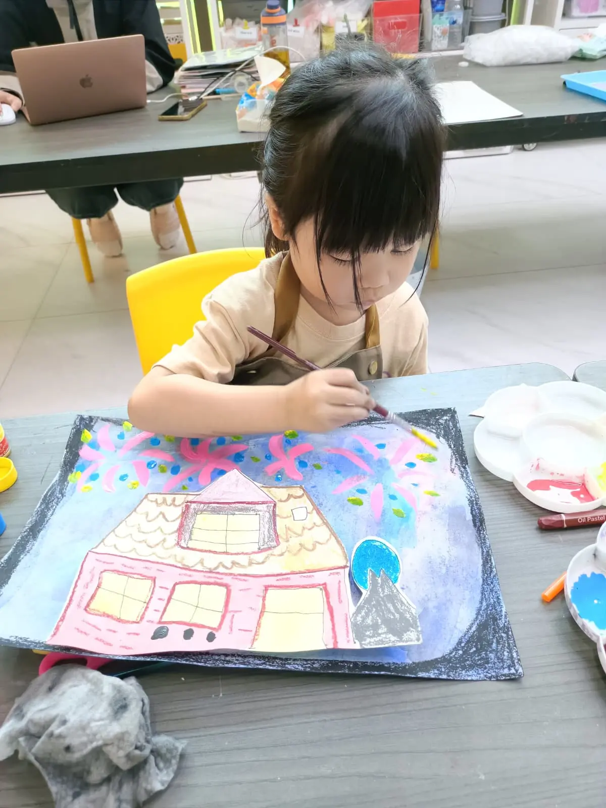 Young child aged 4-6 happily painting during a creative art workshop at Art Journey Singapore