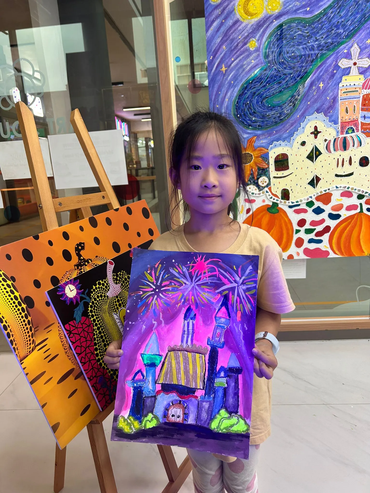 Young child at Art Journey Singapore proudly showing their completed artwork from a creative workshop session