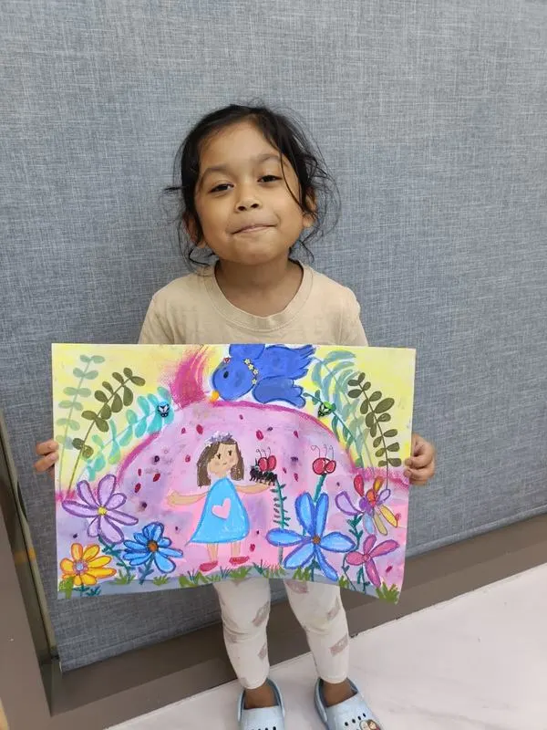Young girl holding a colourful garden and flowers painting created during Art Journey art workshop