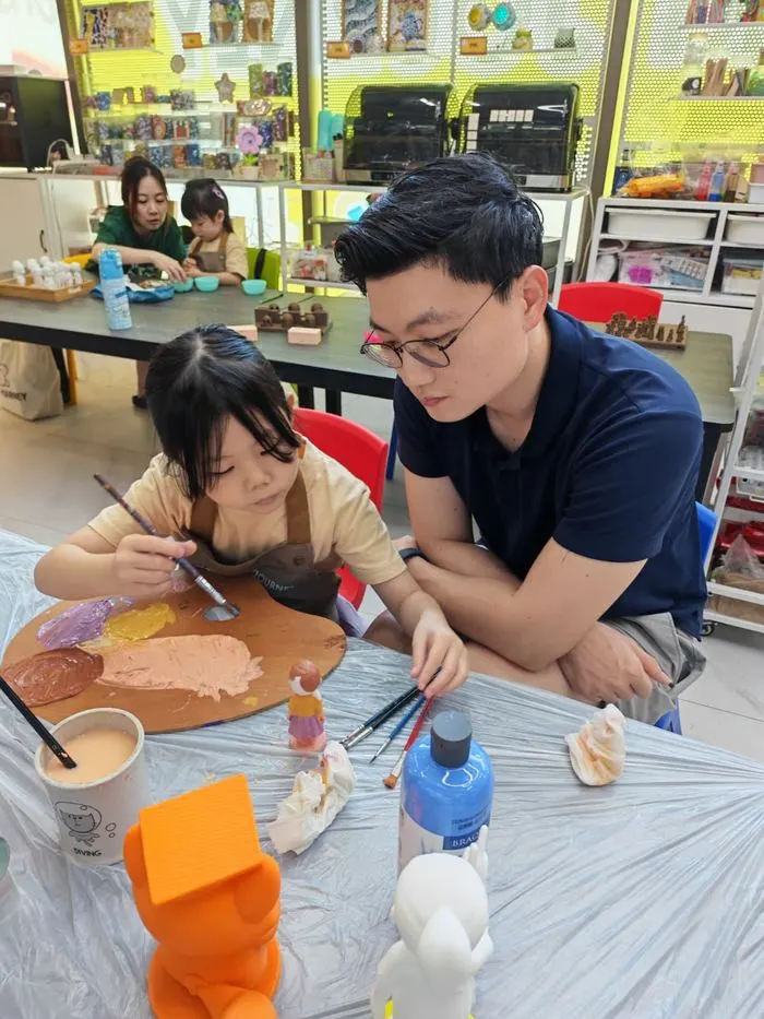 Father and daughter painting figurines together at Art Journey Singapore art jamming studio