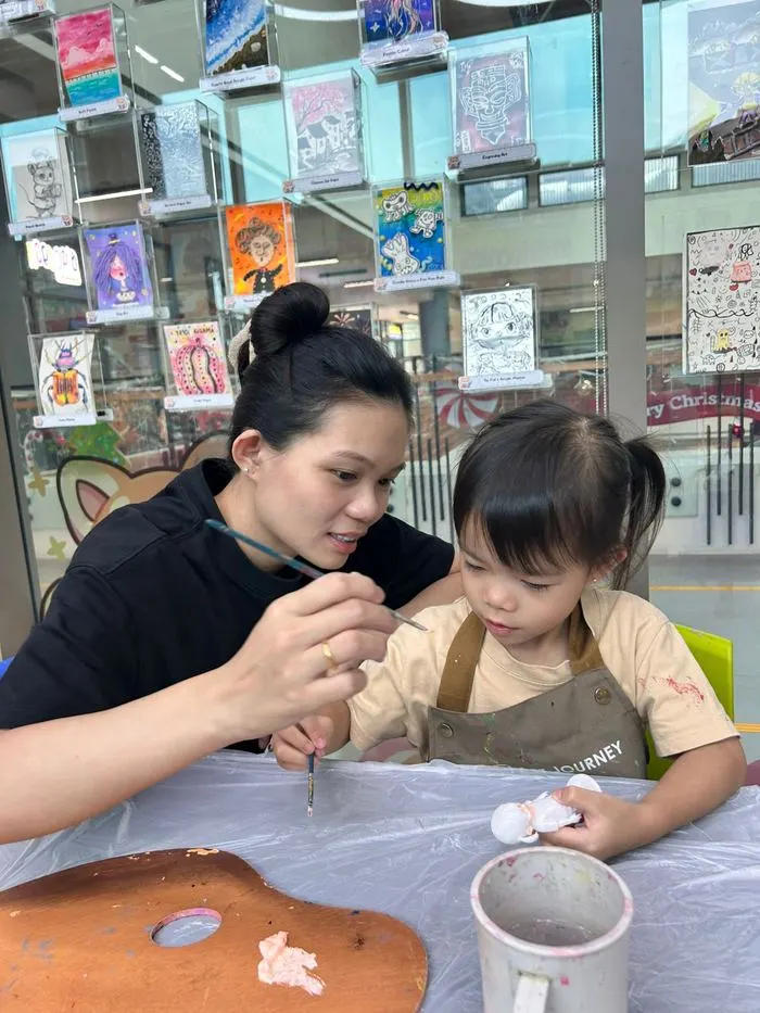 Mother and daughter painting a figurine together during an art jamming session at Art Journey Singapore