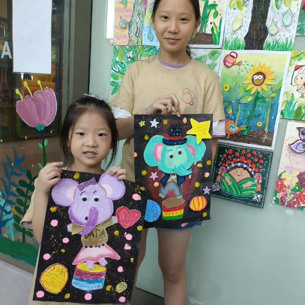 Child proudly showing completed artwork from holiday art workshop