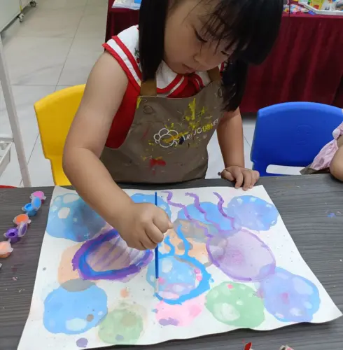 Three-year-old working with chunky brushes at Art Journey Singapore