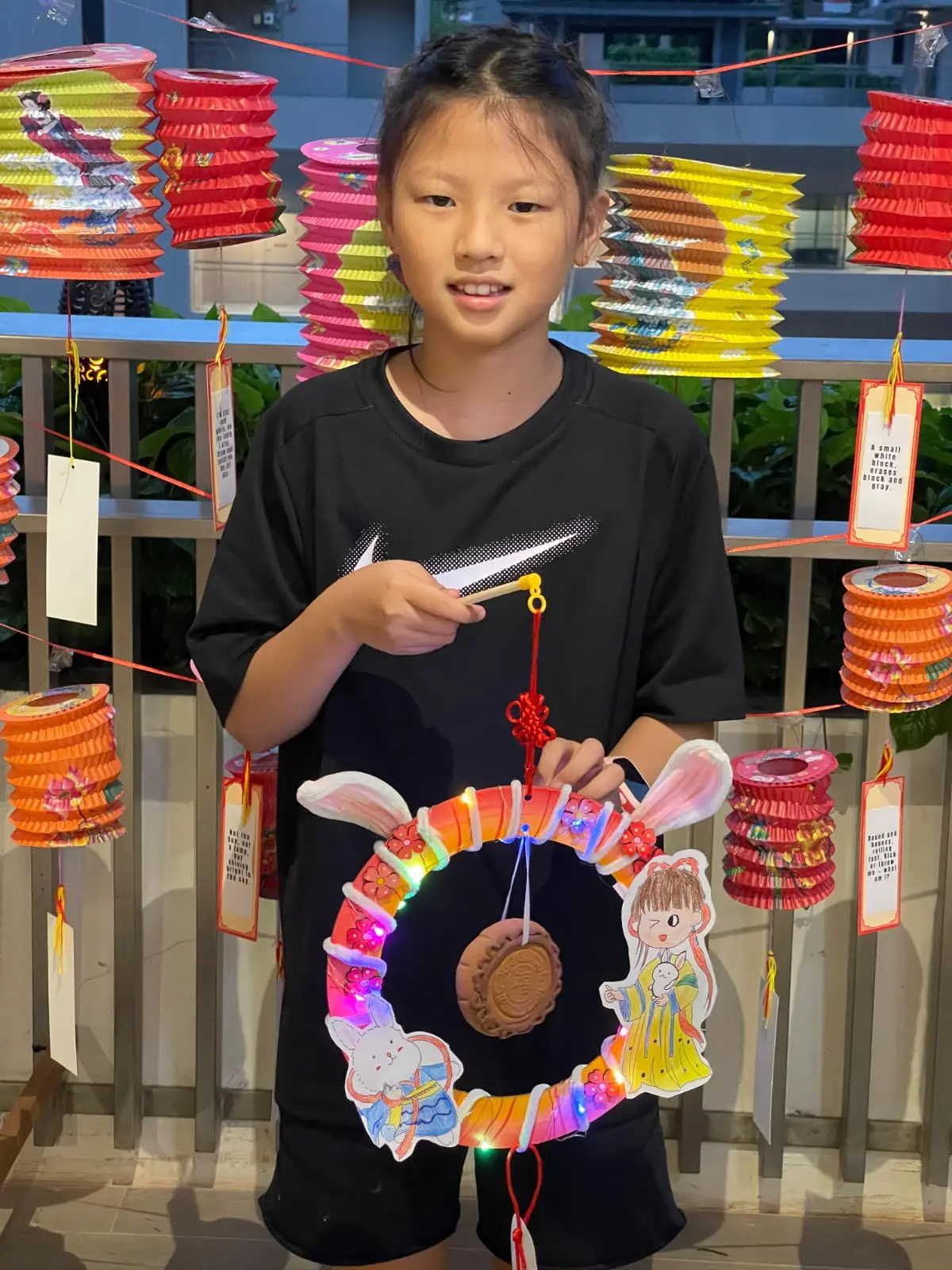 Children displaying their Mid-Autumn Festival art projects including painted lanterns and moon-themed artwork