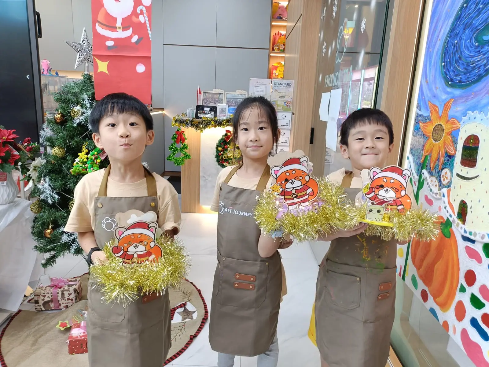 Children proudly holding their handmade Christmas gifts created during an art workshop at Art Journey Singapore