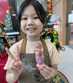 Happy young artist showing her painted 3D figurine at Art Journey kids art workshop in Singapore