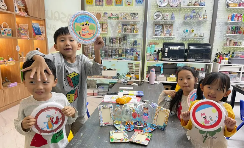 Child focused on creating a mosaic art piece at Art Journey Singapore, looking proud and engaged