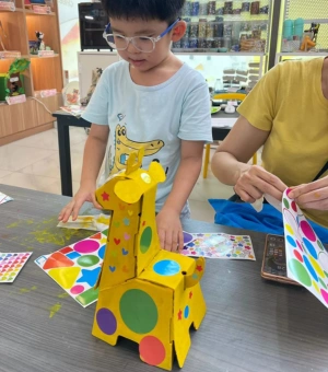 Young creator building a colourful cardboard giraffe craft at Art Journey kids art workshop