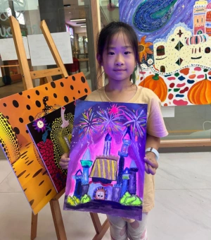 Young artist proudly showing her fireworks castle painting at Art Journey kids art workshop in Singapore