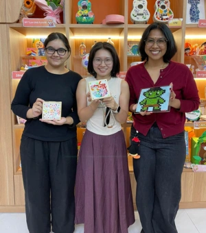 Group of friends showing completed mosaic and sand art pieces at Art Journey Singapore