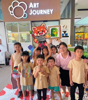 Group of young artists with facilitator posing with Rumi the red panda mascot at Art Journey Singapore