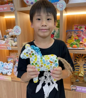Young boy holding a completed mosaic art horse at Art Journey Singapore