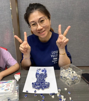 Woman showing her blue and white porcelain-style mosaic art piece at Art Journey Singapore