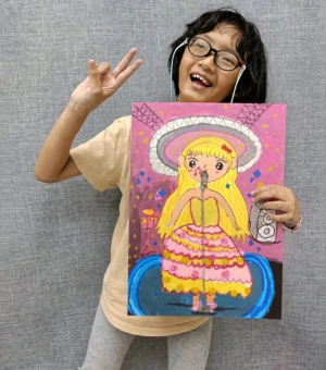 Excited young artist showing her vibrant pop star concert painting at Art Journey kids art workshop