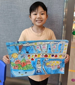 Happy young artist holding a colourful story illustration painting at Art Journey kids art workshop in Singapore
