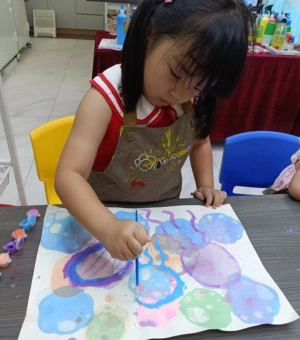 Young creator painting colourful watercolour bubbles at Art Journey toddler art workshop in Singapore