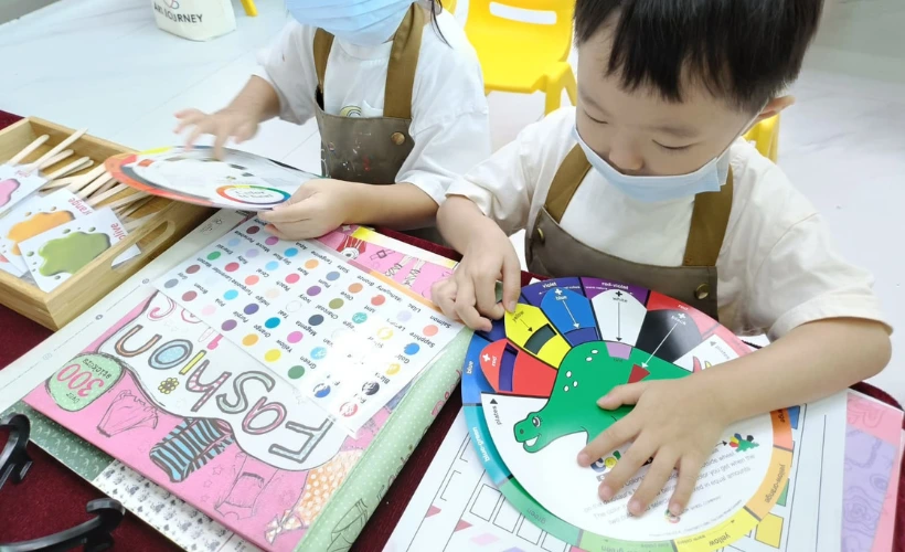 Child proudly holding up a completed colourful painting at Art Journey Singapore beaming with confidence