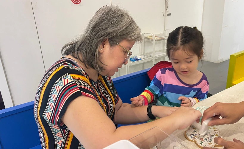 Grandmother and grandchild creating art together at Art Journey Singapore smiling and bonding over creative activity