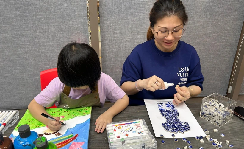 Parent and child sitting together at Art Journey Singapore each painting their own canvas with very different results