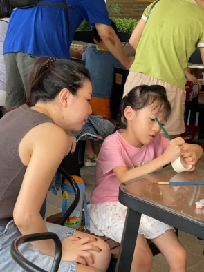 Mother watching her daughter sketch a design during childrens pottery painting