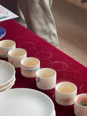 Row of hand painted ceramic cups and plates ready for firing