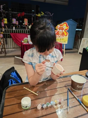Close view of a child painting fine detail onto a ceramic cup