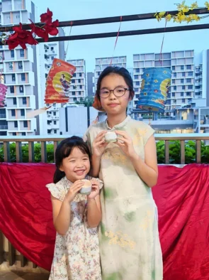 Two girls holding the ceramic cups they painted in Singapore