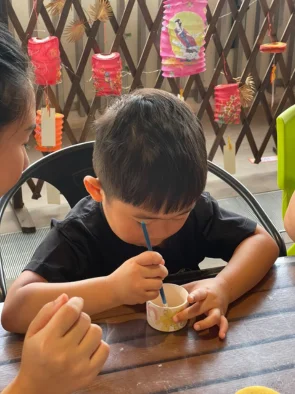 Young boy carefully painting a ceramic cup at a pottery painting session